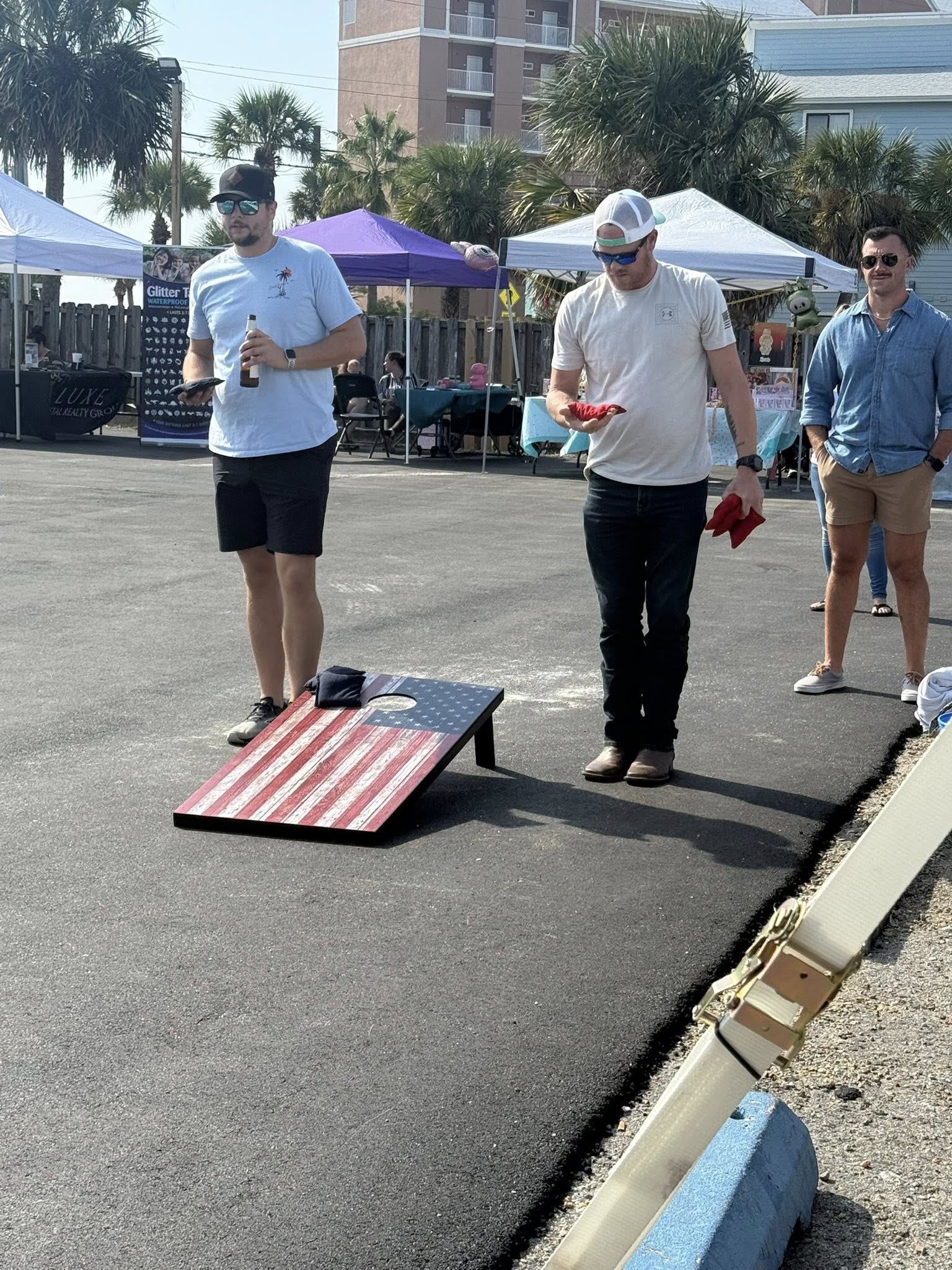 Friends playing cornhole outdoors under tents