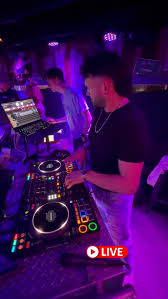 DJ performing at a purple-lit booth during a night event