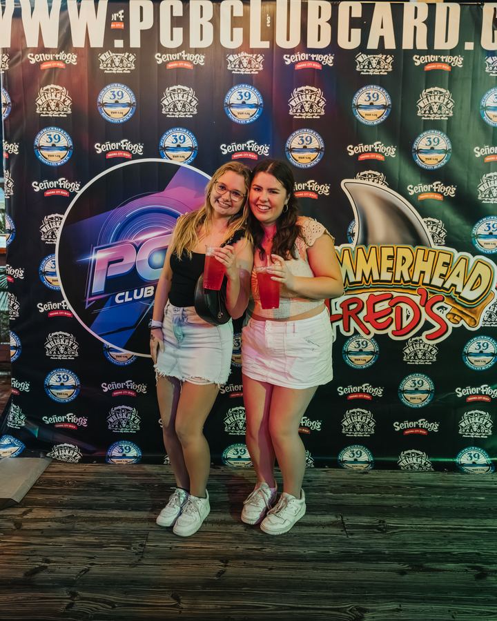 Two friends at the PCB Club Card photo backdrop