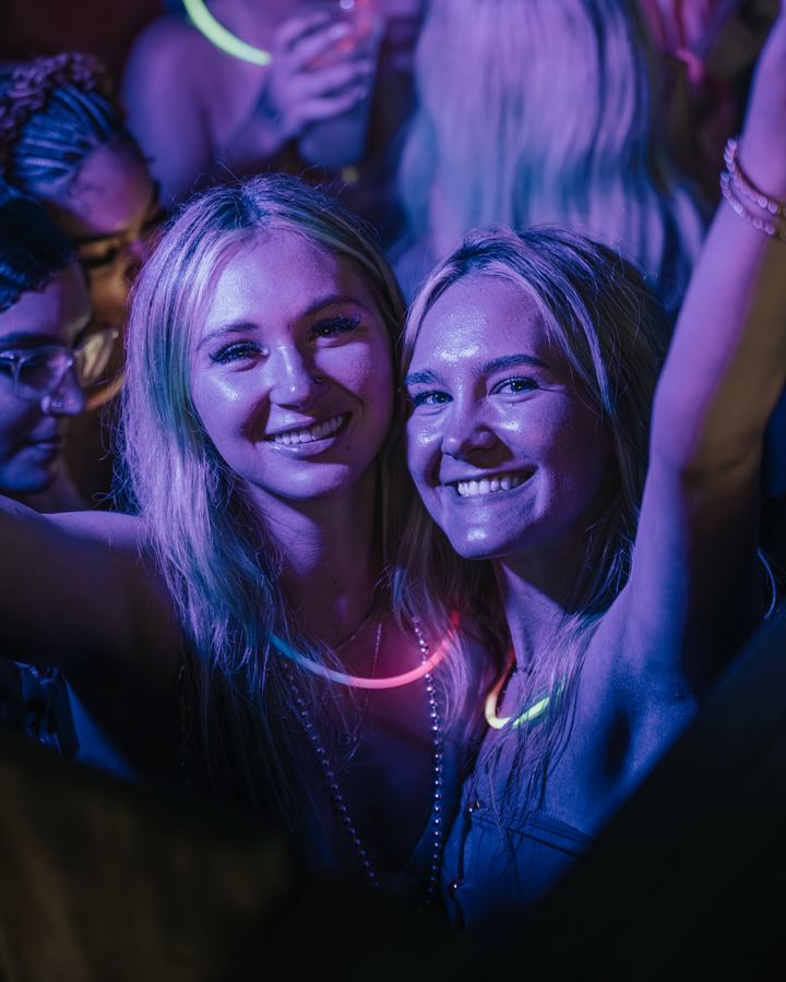 Two friends smiling with glow necklaces